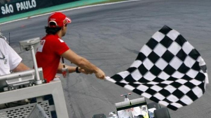 Felipe Massa z týmu Ferrari mává vlajkou při průjezdu Jensona Buttona ze stáje Brawn GP při Velké ceně Brazílie