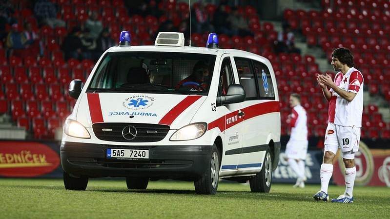 Sanitka odváží z hrací plochy zraněného slávistu Naumova. Vpravo Matej Krajčík.