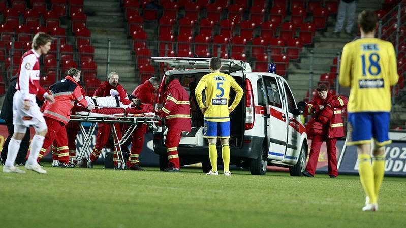 Záchranáři nakládají zraněného slávistu Riste Naumova na nosítkách do sanitky.