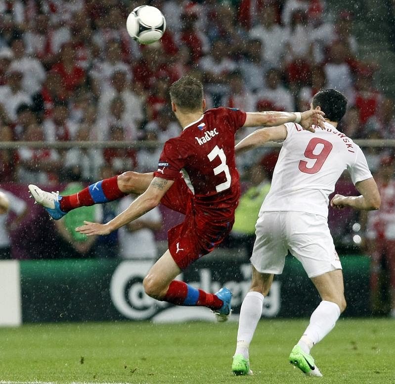 Michal Kadlec akrobatickým zákrokem odkopává míč před Polákem Leawandowskim.