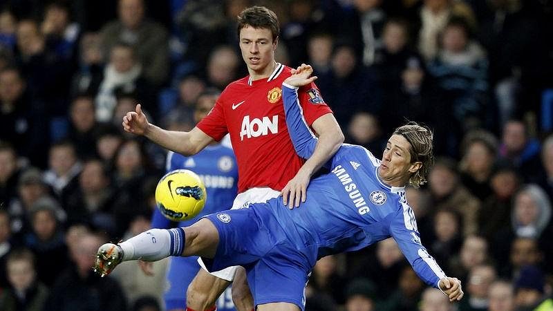 Fernando Torres z Chelsea padá v souboji s Jonny Evansem z Manchesteru United.