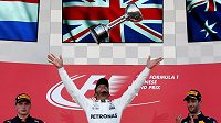 Lewis Hamilton slaví s trofejí pro vítěze japonské velké ceny. Lewis Hamilton slaví s trofejí pro vítěze japonské velké ceny.