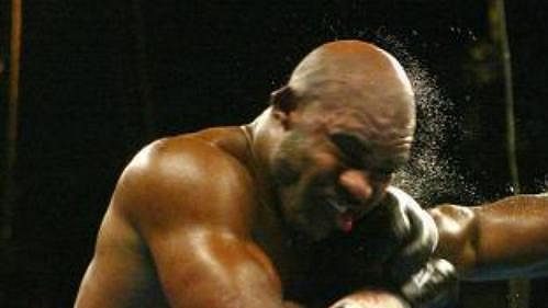 Evander Holyfield dostává od James Toneyho tvrdý pravý hák..