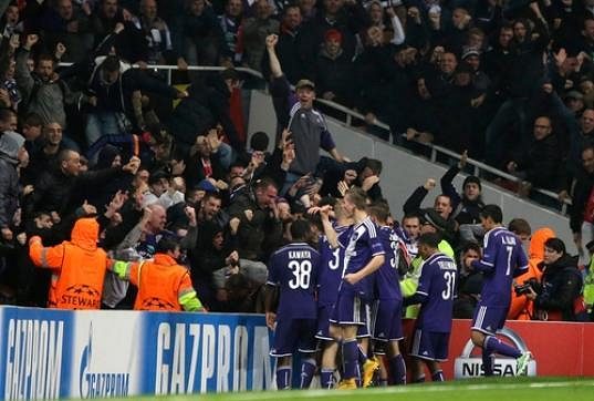 Fotbalisté Anderlechtu slaví s fanoušky vyrovnávací gól Aleksandara Mitroviče na stadiónu Arsenalu v Lize mistrů.