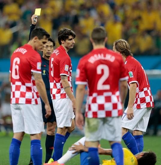 Sudí Juiči Nišimura dává chorvatskému obránci Vedranu Čorlukovi (uprostřed) žlutou kartu.
