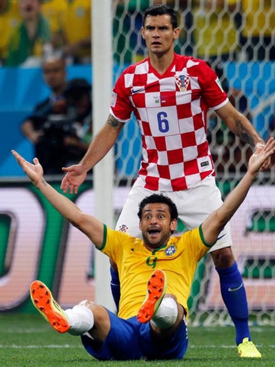 Klíčový souboj ve vápně - Chorvat Dejan Lovren (nahoře) se diví verdiktu sudího Nišimury, který na stadiónu Itaquerao v Sao Paulu odpískal pokutový kop za údajný faul na útočníka Freda.