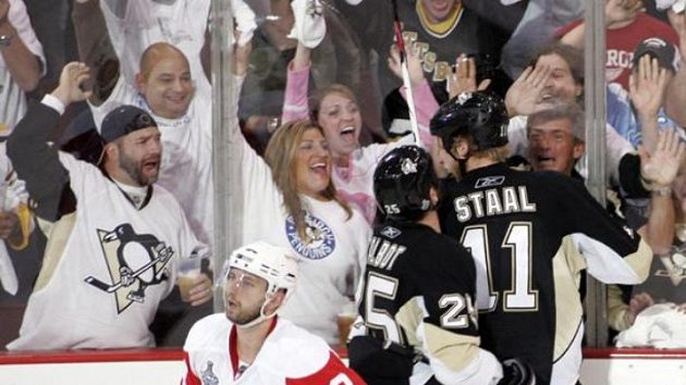 Obránce Detroitu Brian Rafalski před slavícími hráči Pittsburghu Talbotem a Staalem