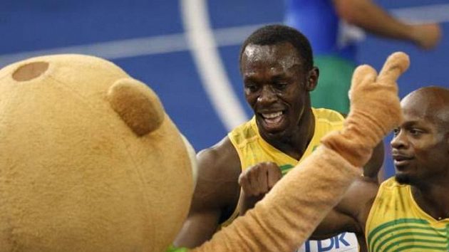 Jamajští sprinteři Usain Bolt (uprostřed) a Asafa Powell oslavují s maskotem berlínského MS vítězství ve štafetě na 4x100 metrů.