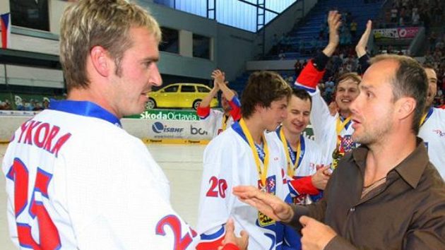 Kapitán extraligové Plzně Martin Straka (vpravo) předává zlaté madaile pro mistry světa českým hokejbalistům.