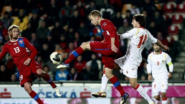 Michal Kadlec (uprostřed) odkopává míč před dotírajícím Dejanem Demjanovičem z Černé Hory.