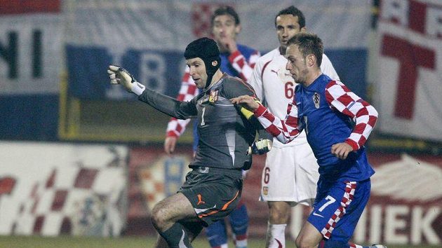 Situace předcházející čtvrtému gólu Chorvatska. Brankář Petr Čech (vlevo) se snaží odklidit míč před Ivanem Rakitičem.