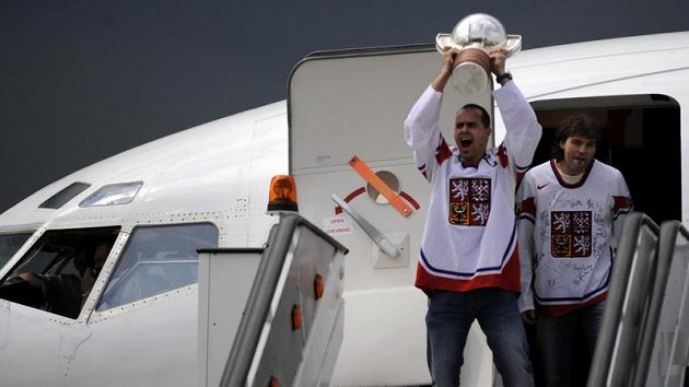 Hokejisté Tomáš Rolinek (s pohárem) a Jaromír Jágr vycházejí z letadla po přistání v Praze.