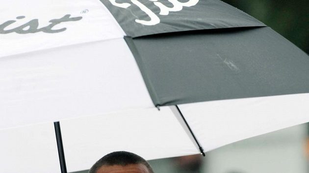 Desetibojař Roman Šebrle se skrývá pod deštníkem během atletického mítinku v Kladně.