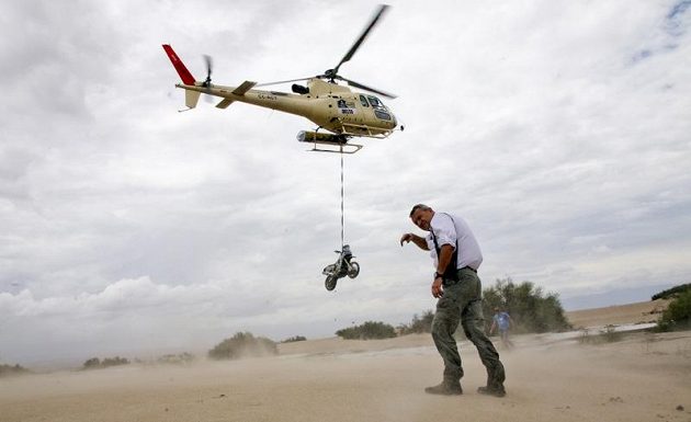 Ředitel Rallye Dakar Etienne Lavigne se kryje před prachem, který rozvířila helikoptéra odvážející motocykl Herva Thierryho z Francie.