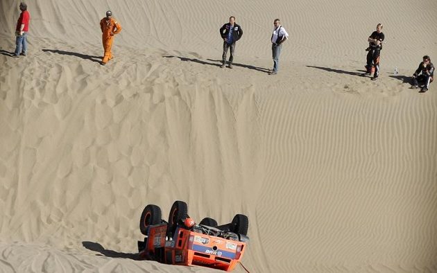 Robby Gordon (vpravo) a Kellon Walch (druhý zprava) se dívají na svůj hummer, který skončil na střeše.