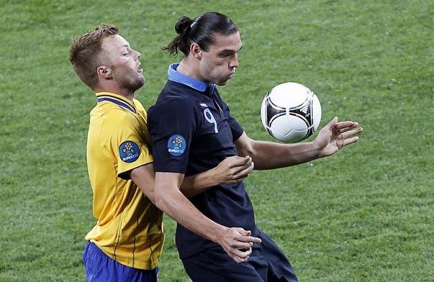 Útočník Anglie Andy Carroll si kryje míč před Sebaastianem Larssonem ze Švédska.