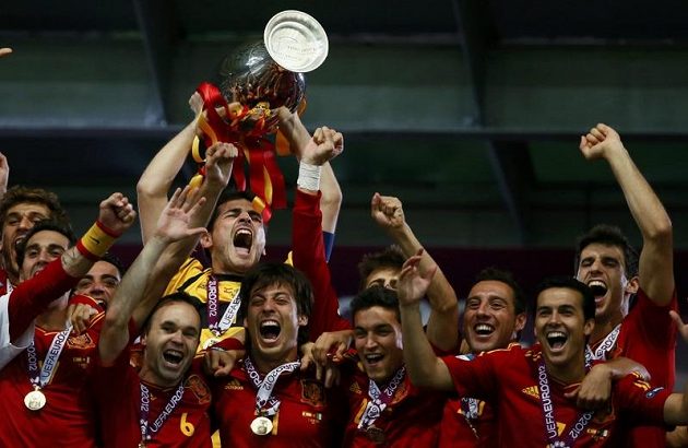 Třetí vítězství na velkém turnaji v řadě! Brankář Španělska Iker Casillas třímá pohár a bouřlivě oslavuje se spoluhráči úspěšnou obhajobu na mistrovství Evropy.