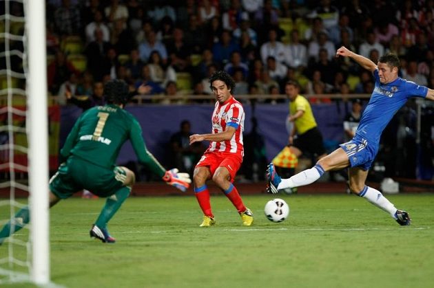 Obránce Chelsea Gary Cahill (vpravo) se marně snaží zblokovat střelu Ardy Turana z Atlétika Madrid, míč se chystá zlikvidovat brankář Petr Čech.