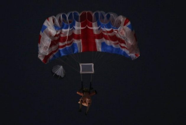 Herec v přestrojení za britskou královnu Alžbětu na padáku nad olympijským stadiónem během zahajovacího ceremoniálu.