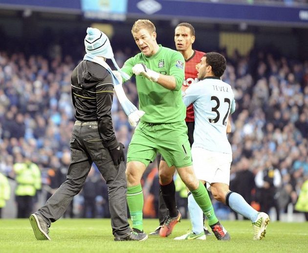Brankář Manchesteru City Joe Hart zastavuje fanouška, který si chtěl vyšlápnout na Ria Ferdinanda z Manchesteru United, jehož drží Carlos Tevez.