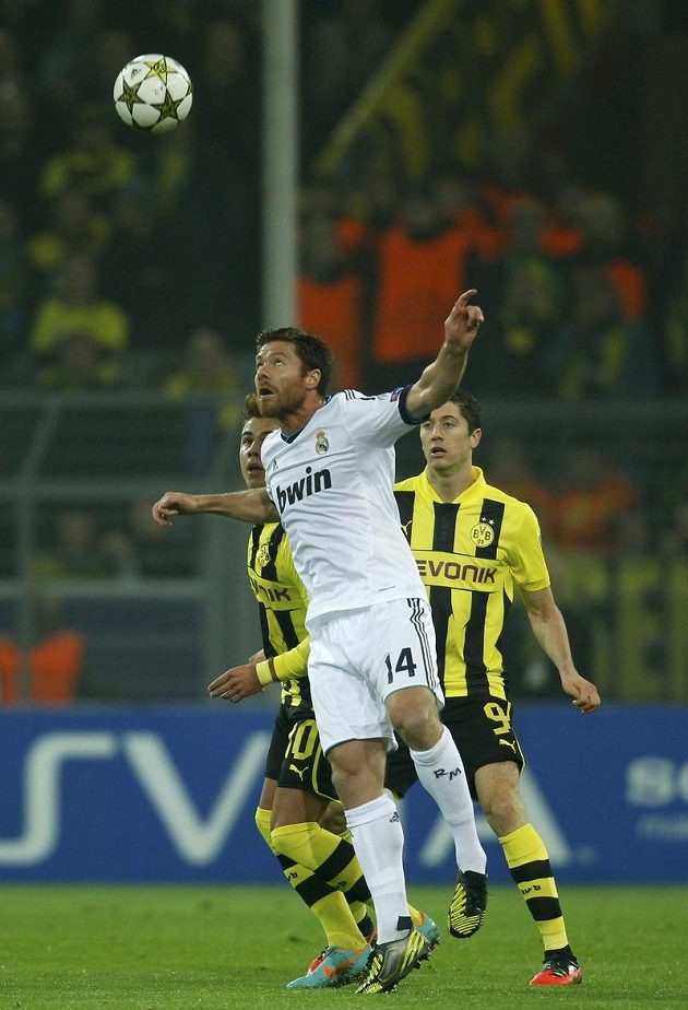 Záložník Realu Madrid Xabi Alonso odhlavičkoval míč před dvojicí fotbalistů Dortmundu Götze - Lewandowski.