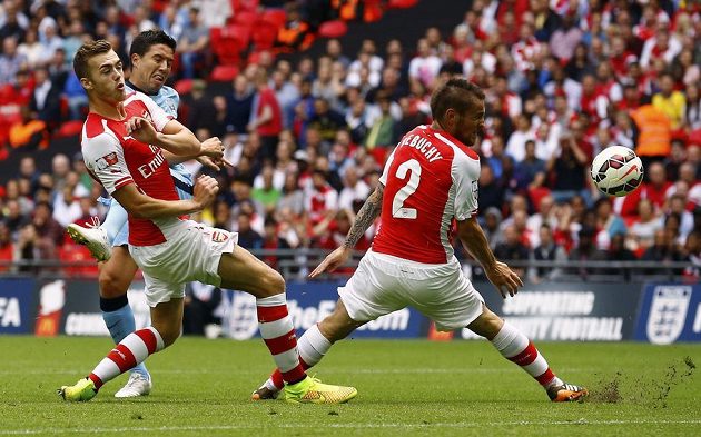 Nasri z Manchesteru City střílí, blokují ho Calum Chambers (vlevo) a Mathieu Debuchy z Arsenalu.