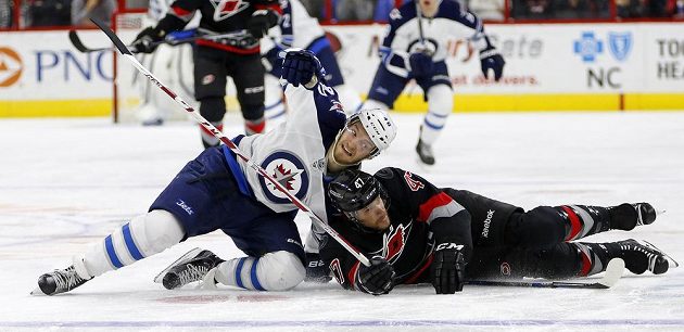 Joel Armia (vlevo) z Winnipegu v souboji s českým zadákem Michalem Jordánem z Caroliny.