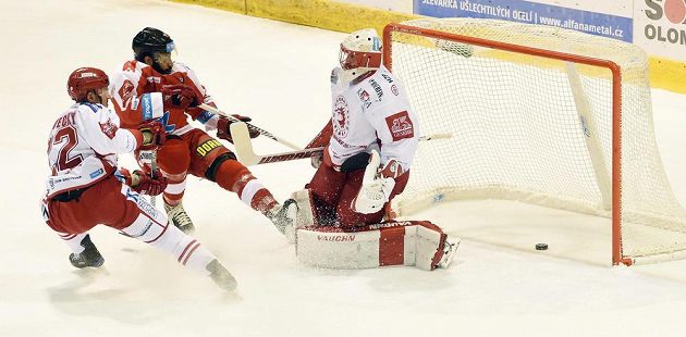 Brankář Třince Šimon Hrubec inkasuje gól z hole olomouckého útočníka Kevina Sundhera. Vlevo přihlíží útočník Ocelářů Vladimír Dravecký.