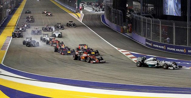 Lewis Hamilton (zcela vpravo) přebírá po startu Velké ceny Singapuru vedení, jeho stájový kolega Nico Rosberg (na snímku uprostřed nahoře) musel po problémech s řazením v zahřívacím kole vyrazit na trať z boxové uličky.