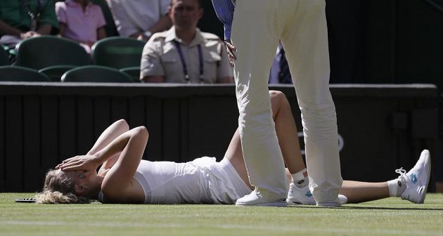 Česká tenistka Kateřina Siniaková leží s bolestnou grimasou na trávě ve Wimbledonu.