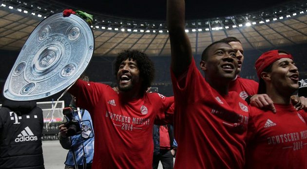Zleva obránce Dante s trofejí, levý bek Alaba a záložník Thiago slaví 24. mistrovský titul Bayernu.