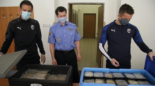 Asistent trenéra fotbalové Viktorie Marek Bakoš (vlevo) se záložníkem Janem Kopicem předávají obědy jednohomu z městských strážníků v Plzni.