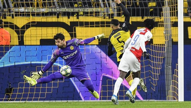 Brankář Dortmundu Roman Bürki zneškodnil šanci Slavie po hlavičce Petera Olayinky (vpravo).