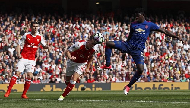 Fotbalista Arsenalu Rob Holding odehrává hlavou míč před hráčem Manchesteru United v utkání Premier League.