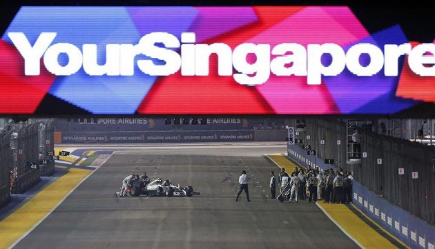 Pořadatelé tlačí vůz Nika Rosberga zpět do boxové uličky poté, co německý pilot Mercedesu během zahřívacího kola Velké ceny Singapuru kvůli problémům s řazením zůstal stát na trati.