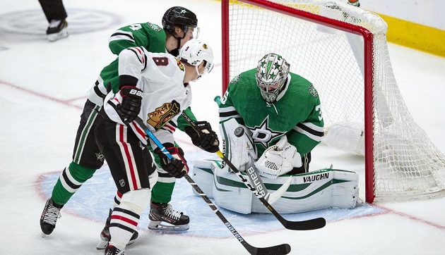 Útočník Chicaga Blackhawks Dominik Kubalík (8) sleduje, jak skončí jeho pokus o dorážku před brankou Dallasu. Tísní jej obránce Miro Heiskanen (4) a zasáhnout se snaží brankář Anton Chudobin (35).