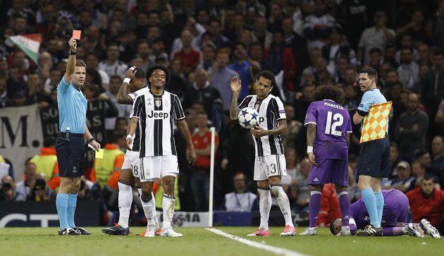 Rozhodčí Felix Brych ukazuje červenou kartu Juanovi Cuadradovi z Juventusu. Vpravo klečí na trávníku zadák Realu Sergio Ramos.