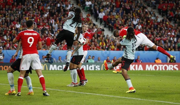 Ashley Williams (ve výskoku vpravo) střílí hlavou vyrovnávací gól ve čtvrtfinálové partii s Belgií.