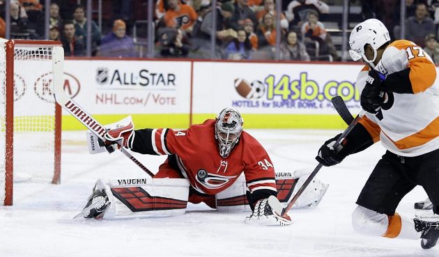 Gólman Caroliny Hurricanes Petr Mrázek v akci, likviduje šanci Simmondse z Philadelphie v utkání NHL.