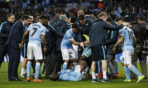 Ležící zraněný Yaya Toure z Manchesteru City se spoluhráči po úspěchu v penaltovém rozstřelu s Liverpoolem.