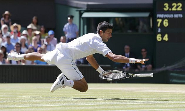 Novak Djokovič ze Srbska při akrobatickém zákroku v semifinále Wimbledonu s Francouzem Richardem Gasquetem.
