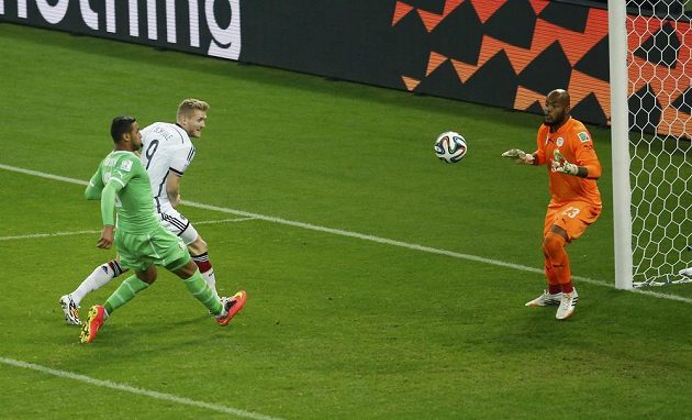Německý fotbalista André Schürrle (v bílém dresu) střílí gól alžírskému brankáři Raísovi Mbulhimu.