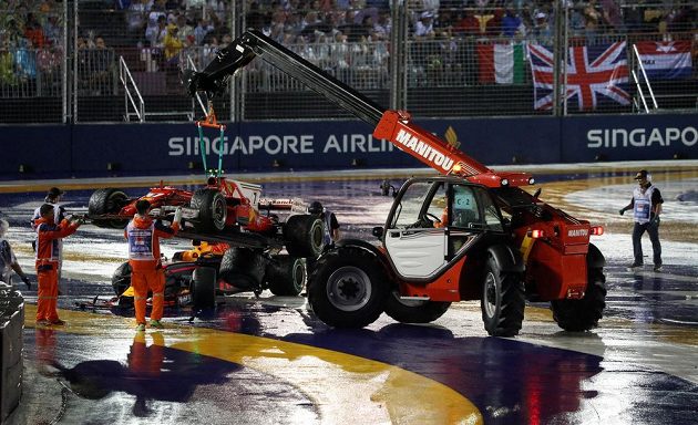 Jeřáb uklízí po startu Velké ceny Singapuru monoposty Kimiho Räikkönenena, Maxe Verstappena a Sebastiana Vettela.