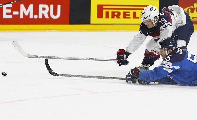 Americký hokejista Clayton Keller se natahuje za pukem, touš se snaží během čtvrtfinále mistrovství světa zasáhnout i Fin Atte Ohtamaa.