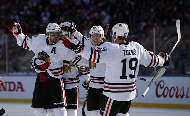 Patrick Sharp (vlevo) z Chicaga oslavuje gól proti Washingtonu, s ním jsou na snímku kapitán Jestřábů Jonathan Toews (19) a další spoluhráči. Podmalování očí je typickým doprovodem venkovních zápasů Winter Classic.
