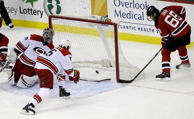 Útočník New Jersey Jaromír Jágr překonává gólmana Caroliny Cama Warda. Nezabránil mu v tom ani obránce Ron Hainsey.