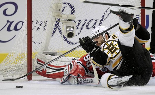 Patrice Bergeron z Bostonu se snaží v akrobatické pozici vyzrát na Coreyho Crawforda v brance Chicaga v úvodním finále Stanley Cupu.