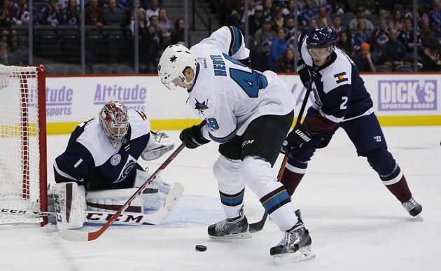 Tomáš Hertl ze San Jose před brankářem Colorada Semjonem Varlamovem. Vpravo Nick Holden.