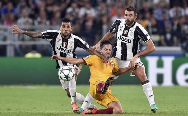 Hráči Juventusu Dani Alves a Andrea Barzagli a proti nim Paolo Sarabia ze Sevilly.