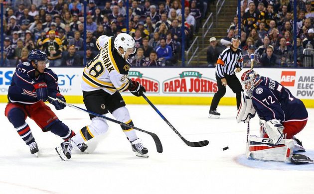 Bostonský David Pastrňák (88) mezi obráncem Columbusu Ryane Murrayem (27) a brankářem Sergejem Bobrovským.